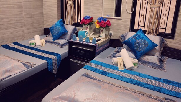 Een hotelkamer met twee bedden, een kaptafel, een spiegel, een ventilator en een vaas met bloemen.
