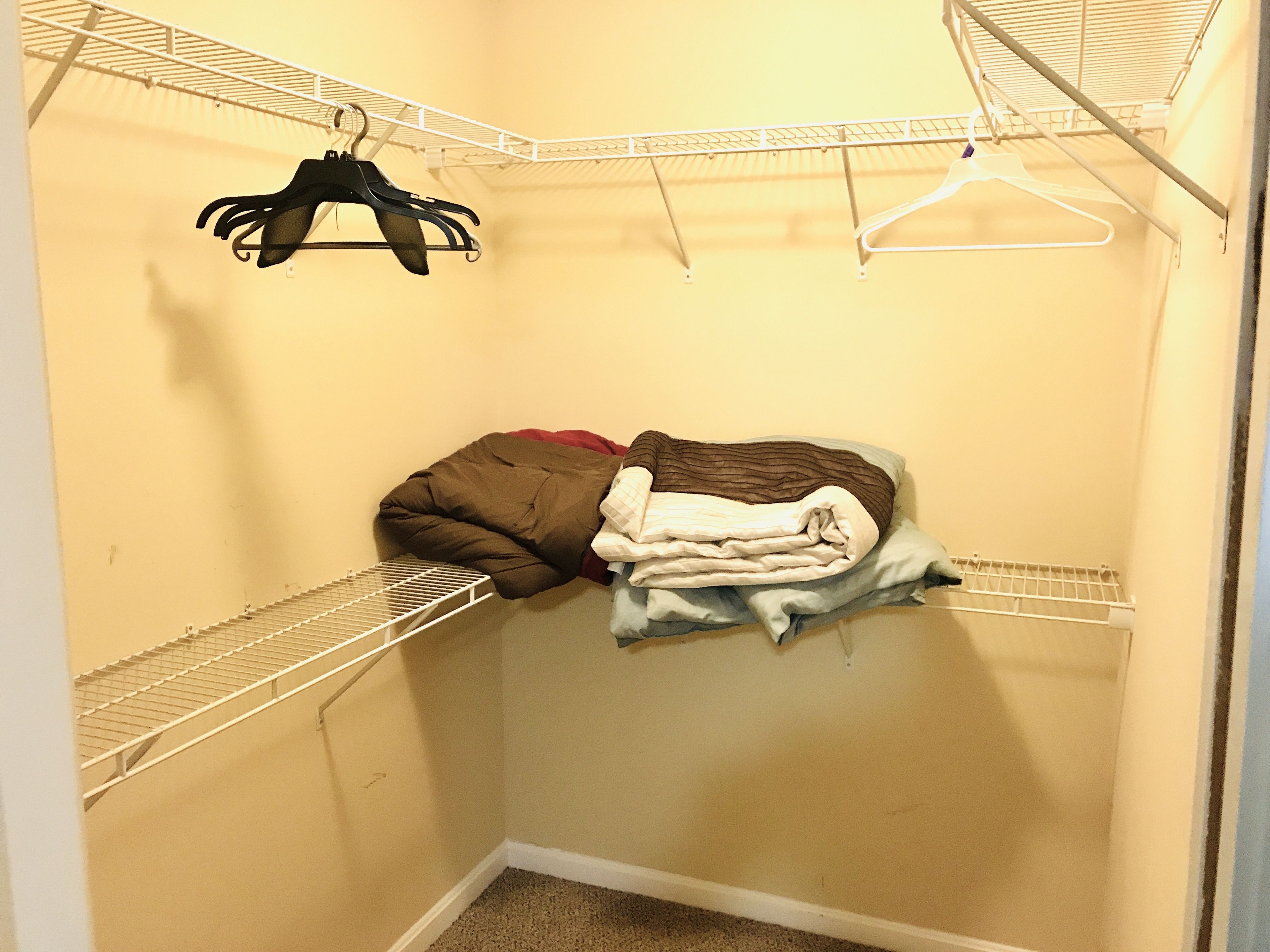A walk-in closet with metal shelves, a hanging rack, and a folded blanket.