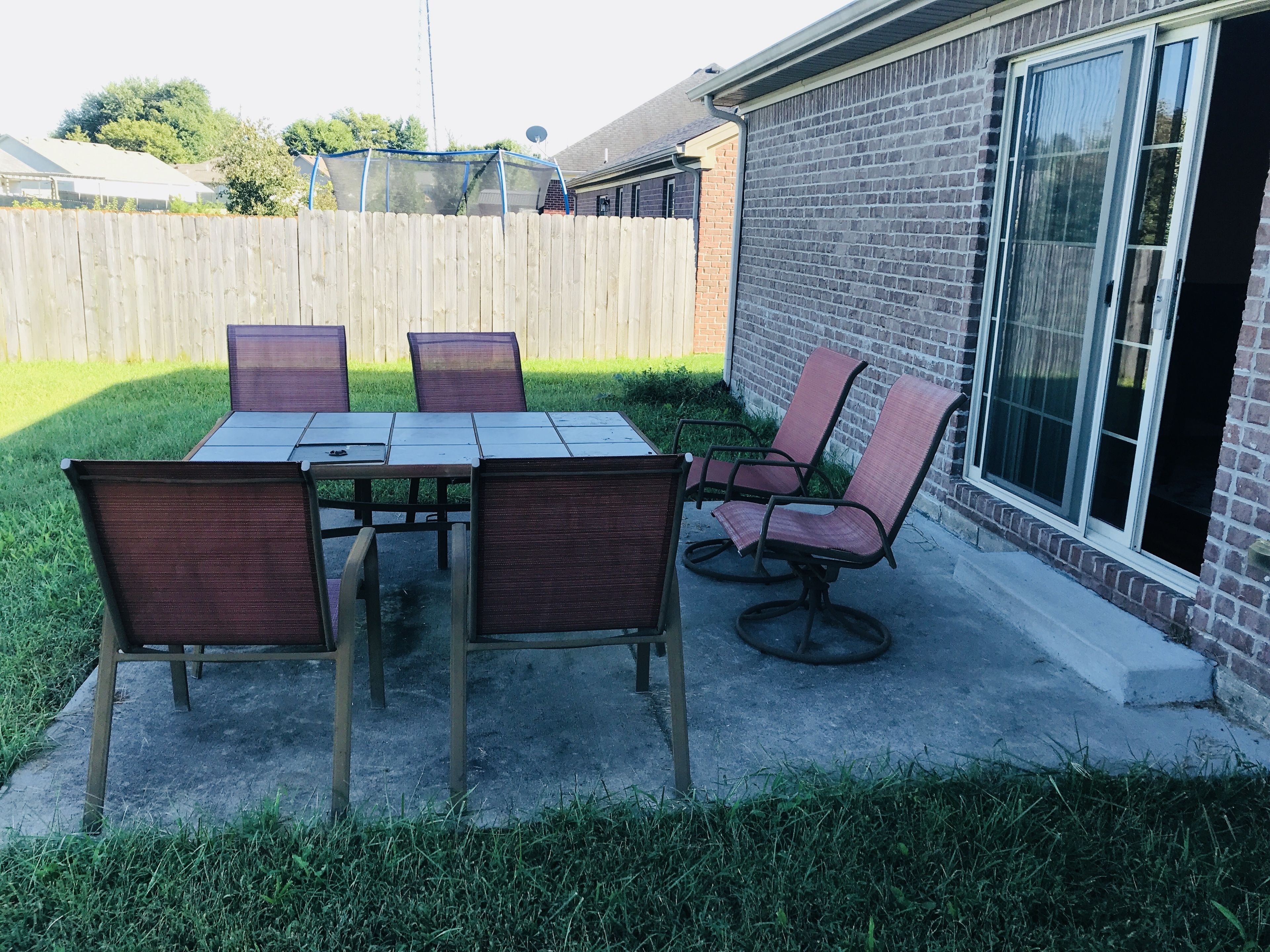 An outdoor patio with a table and chairs, a brick wall, and a wooden fence.
