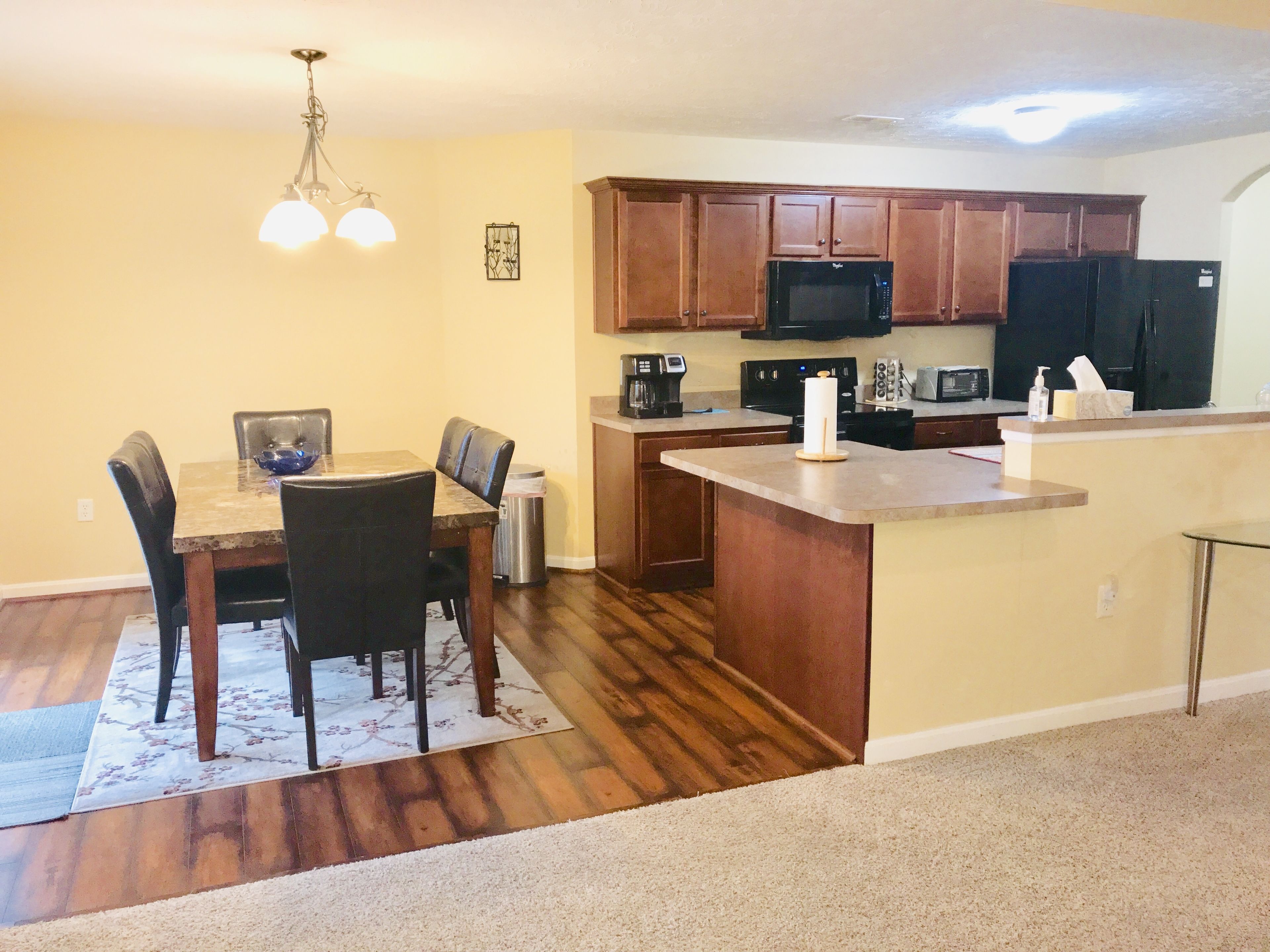 A modern kitchen with wooden cabinets, a microwave, stove, and a refrigerator.