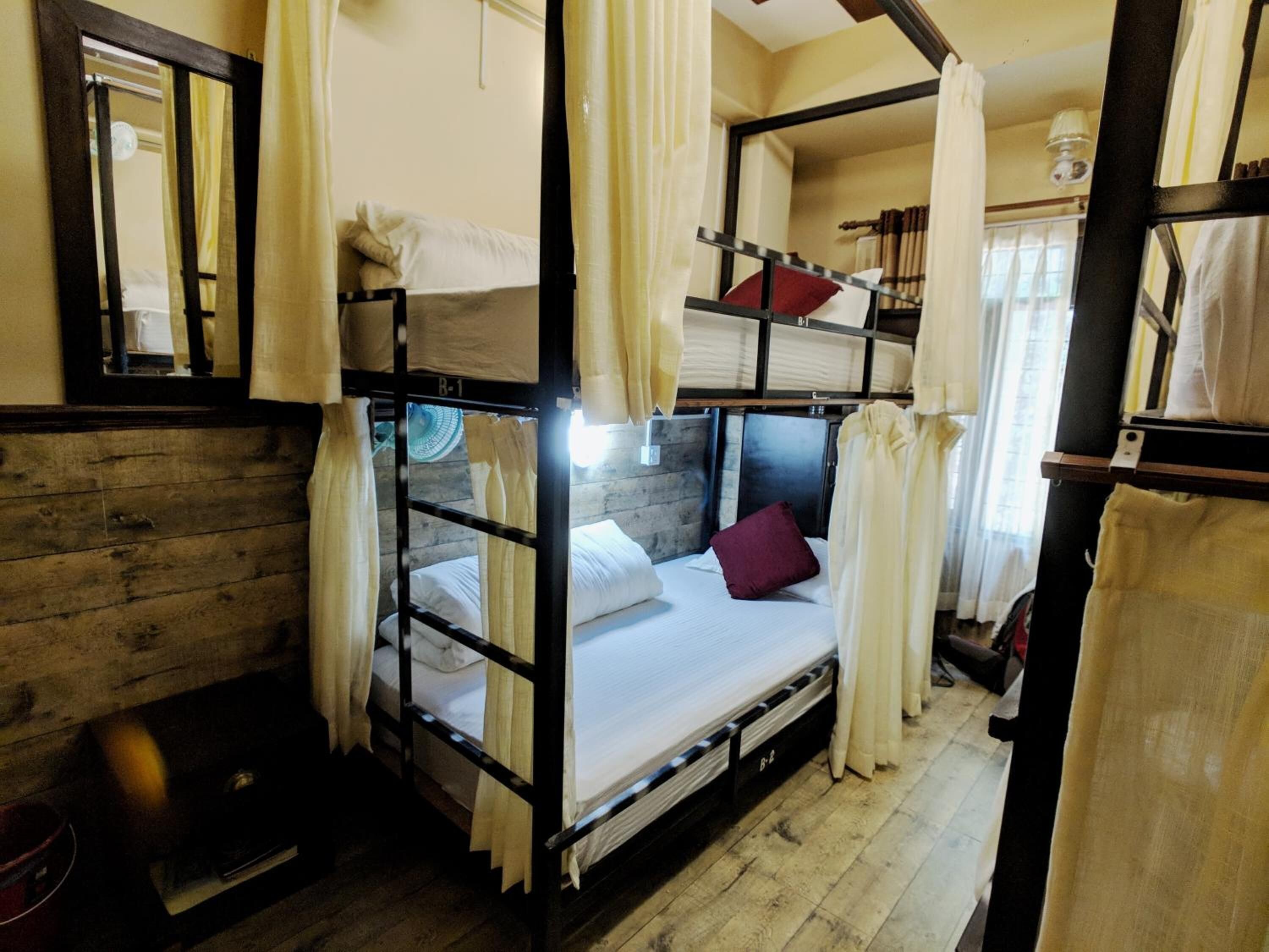 A bunk bed room with wooden walls, a mirror, and curtains.