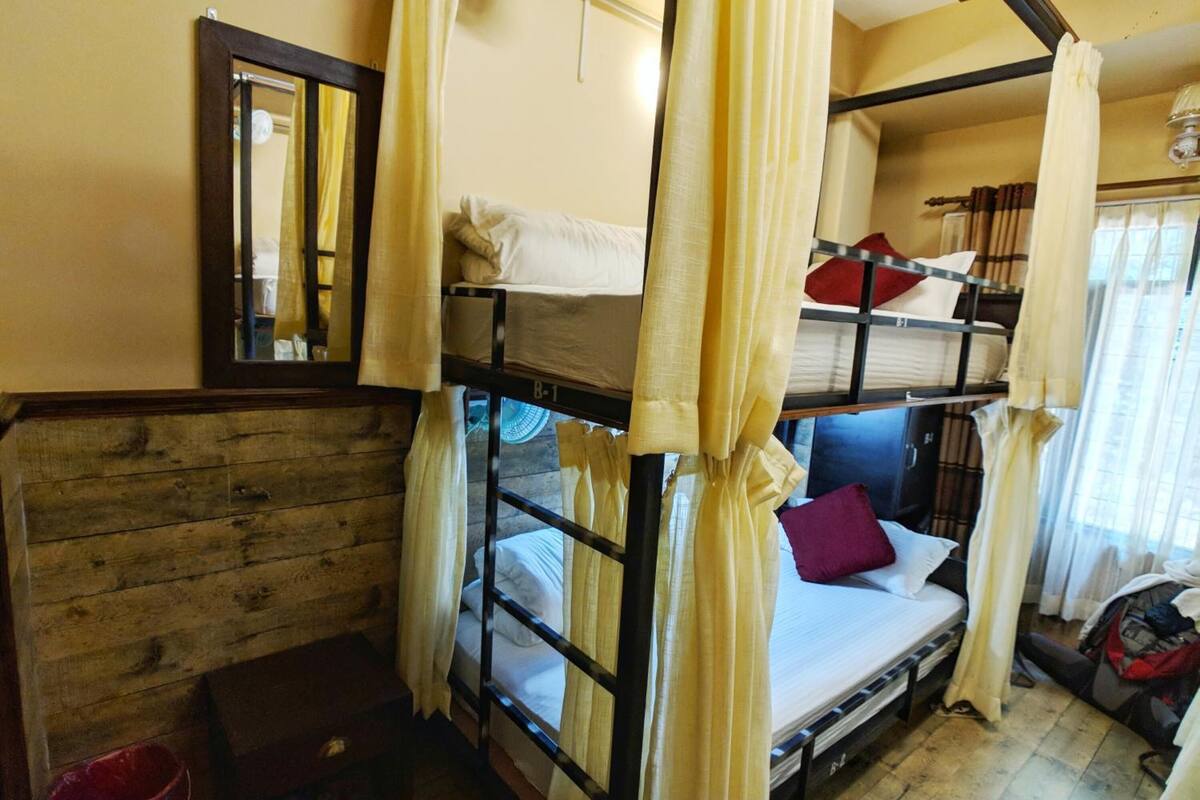 A bunk bed room with a wooden wall, a small wooden chest, and a red bucket.