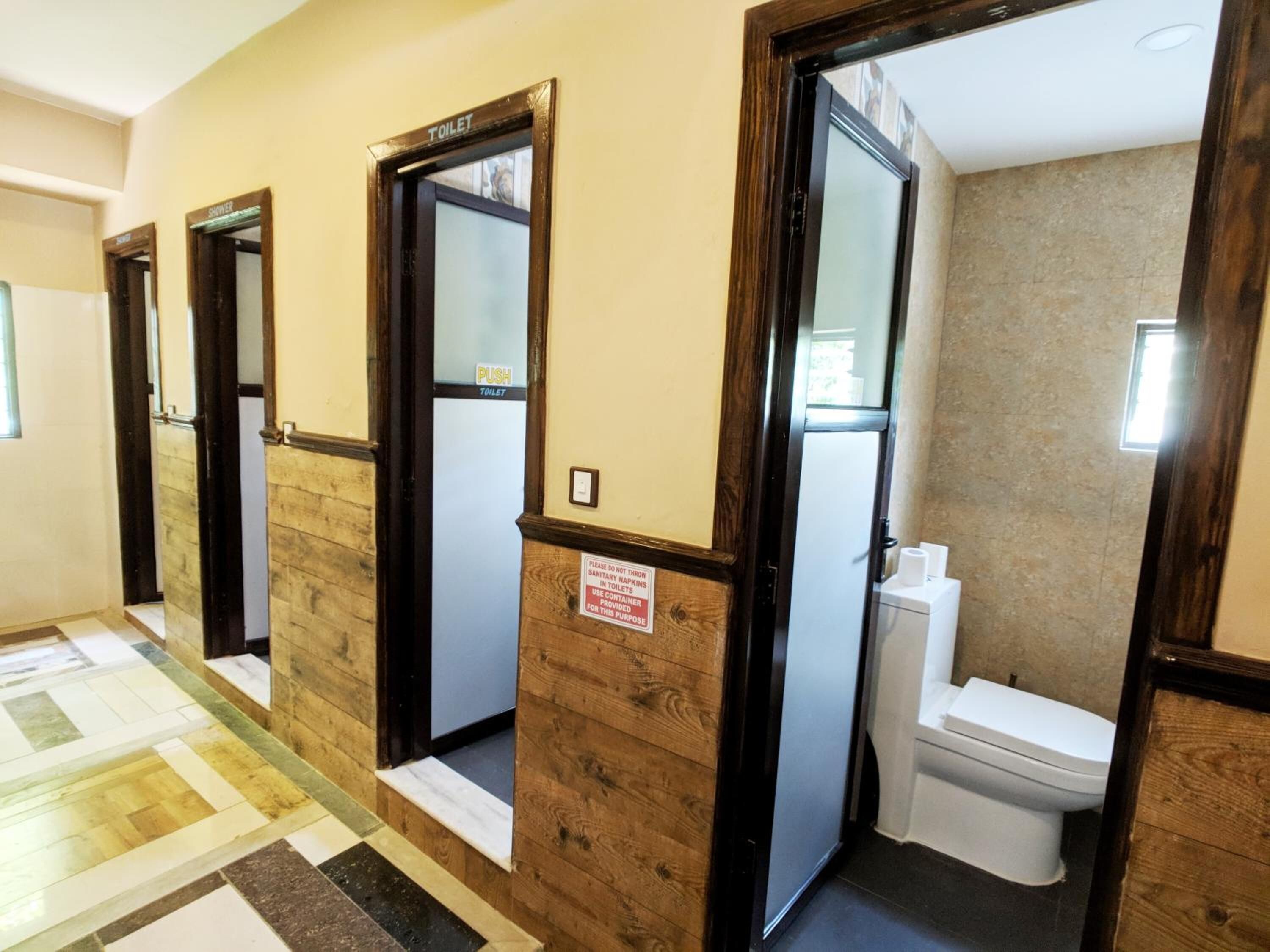 Un couloir d’hôtel avec des portes en bois donnant accès à une salle de bain.