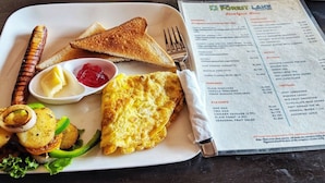 A breakfast tray with toast, scrambled eggs, sausage, and a menu. - Hotel Forest Lake Backpackers' Hostel (Pokhara)