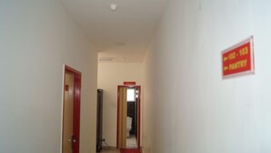 Un pasillo estrecho con una puerta roja a la izquierda y un letrero que indica una habitación en el primer piso.