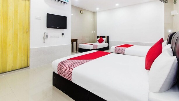 Una habitación de hotel con dos camas, televisión, aire acondicionado y puerta de madera.