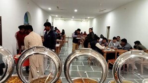 A cafeteria with round stainless steel serving trays and tables.