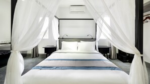 A modern bedroom with a large bed, white canopy, bedside tables, and a wall-mounted air conditioning unit. - Hotel De L'Homme (Phnom Penh)