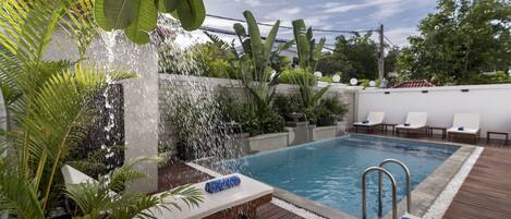 Alberca al aire libre, sombrillas en la alberca y camastros