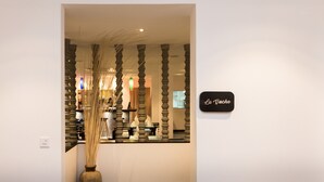 A reception area with a large vase, a sign reading "La Jache," and a decorative wall with vertical elements. - Hotel De L'Homme (Phnom Penh)