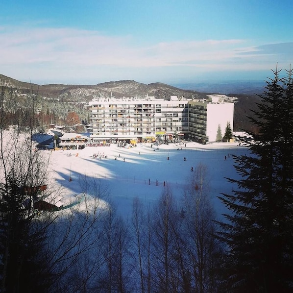 A hotel with multiple floors, a ski slope in the foreground, and mountains in the background. - Chalet Hotel Les Marmottes (Montferrier)