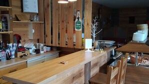 Uma área de bar com balcão comprido, luminárias pendentes e um quadro de cardápio.