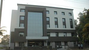 A modern multi-story building with a flat roof, large windows, and a covered entrance area. - Hotel Kanan (Gandhinagar)