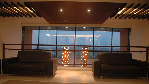 A spacious room with two sofas facing a large window with a view of a cityscape. - Hotel Kanan (Gandhinagar)