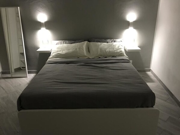 Un letto con una coperta scura e due abat-jour.