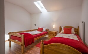A bedroom with two wooden beds, a skylight, and a small bedside table with a lamp. - Apartment in the house Heidinger (Oberaudorf)