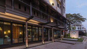Un hotel moderno con una zona de estar exterior cubierta, ventanas amplias y una entrada bien iluminada.