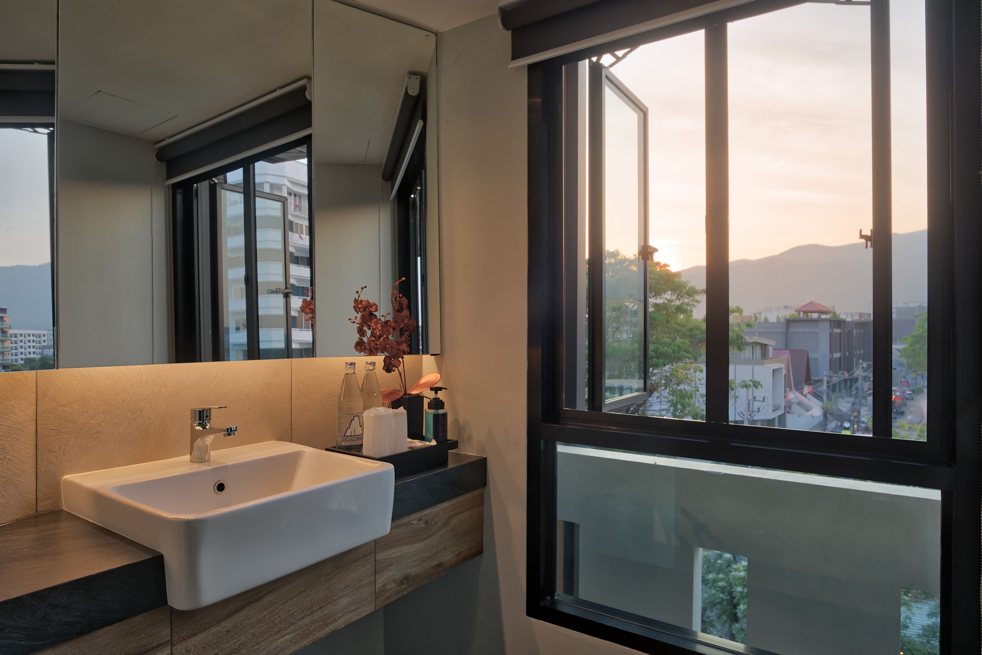 A modern bathroom with a large window, a sink, and a mirror.