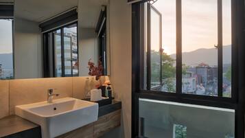 A modern bathroom with a large window, a sink, and a mirror.