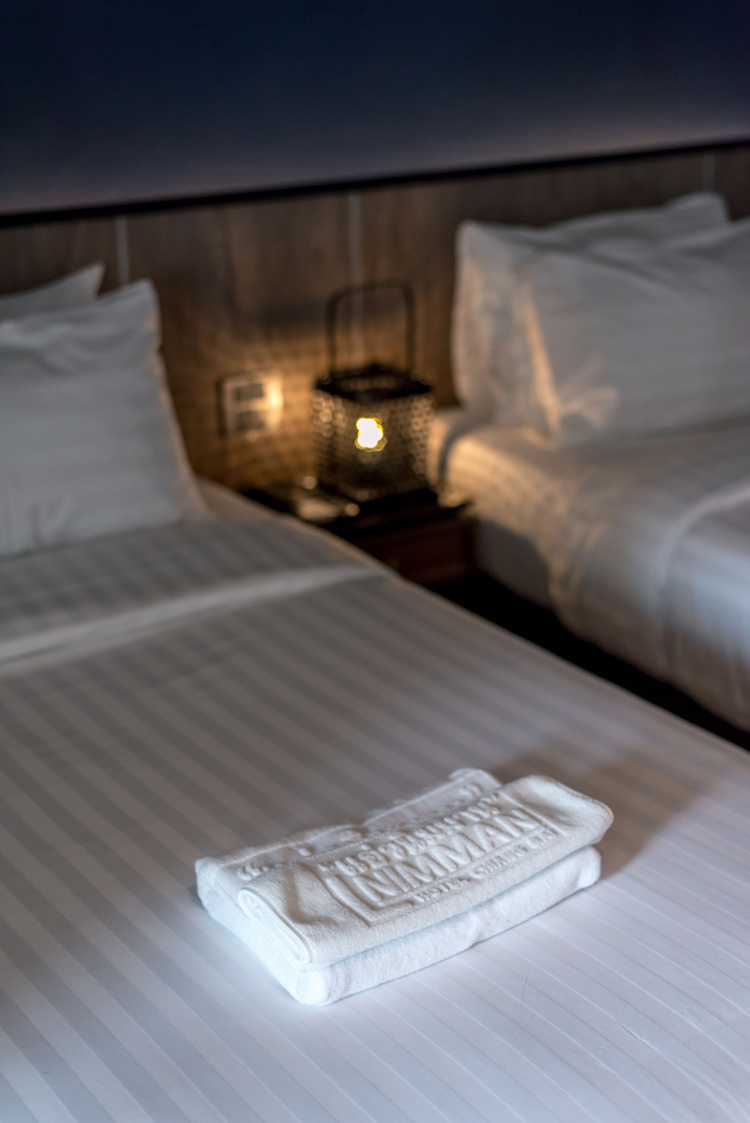 Una habitación de hotel con una cama bien hecha, una lámpara de noche y una mesita de noche.