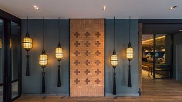 A modern interior with hanging lantern-style lights, a brick-patterned wall, and a wooden floor.