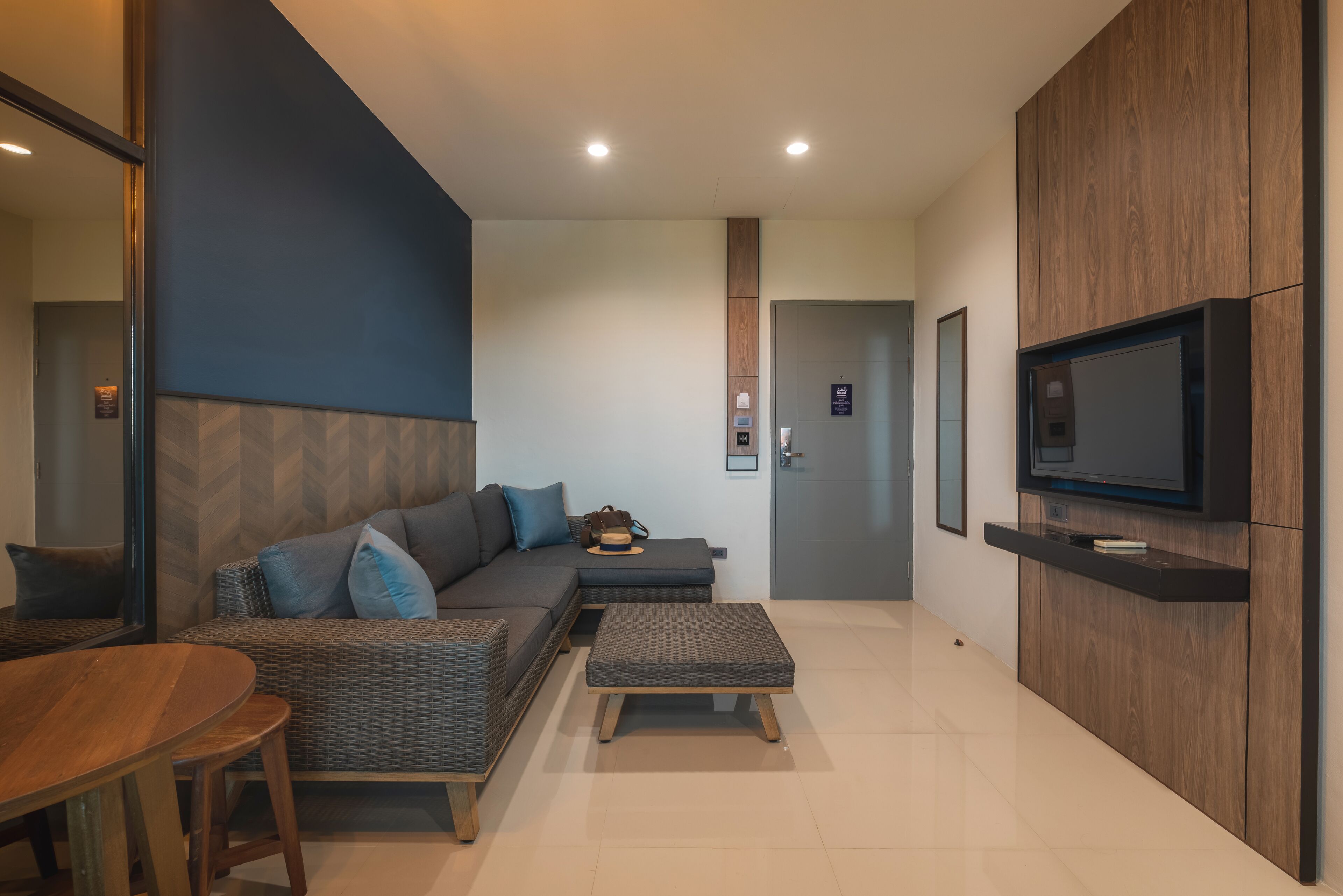 Una sala de estar moderna con un sofá, un reposapiés y un televisor de pantalla plana montado en un mueble de madera.