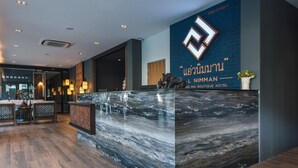 Zona de recepción de un hotel con mostrador de mármol, suelo de madera y un gran cartel en la pared.
