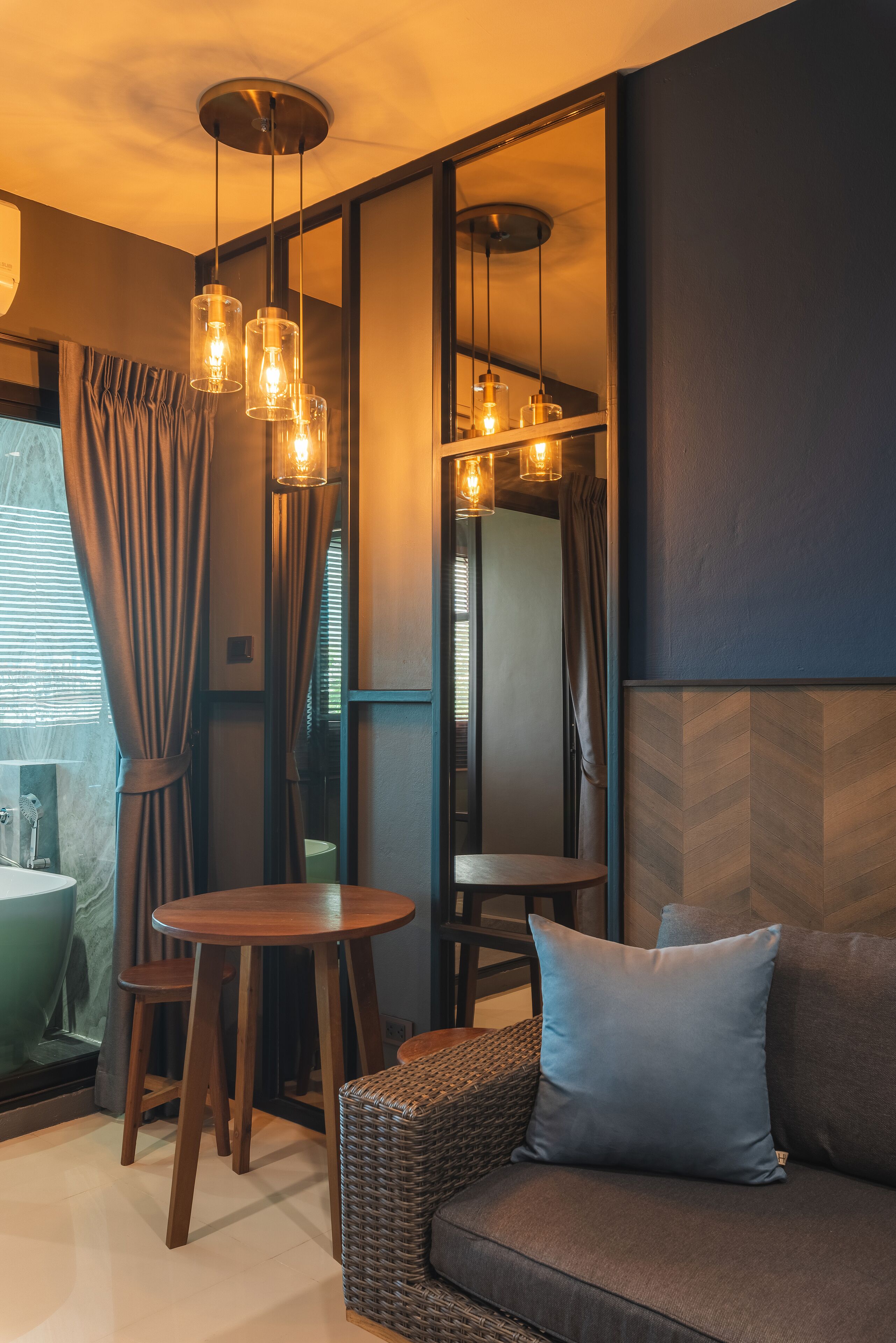 Une pièce moderne avec un canapé, une table ronde en bois et un luminaire suspendu.