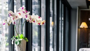 Un interior moderno con encimera de mármol, un florero blanco con orquídeas, un taburete de madera y una silla estampada.