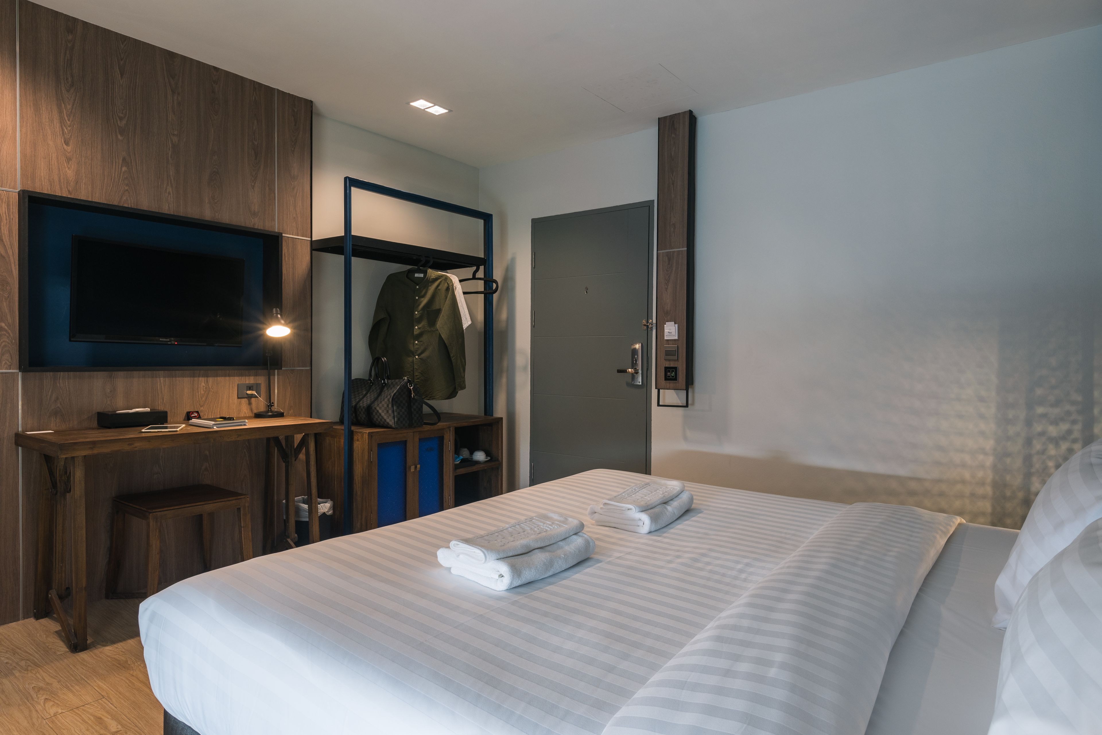 Una habitación de hotel con cama, escritorio, televisión, armario y puerta.