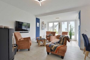 Uma sala de estar moderna com televisão de tela plana, dois sofás, uma mesa de centro e um rack para TV.