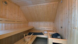 Un sauna avec des bancs en bois, ainsi qu’un banc muni d’une serviette et d’un seau.