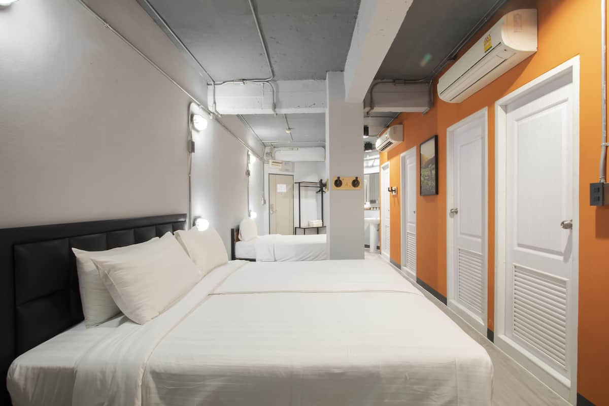 A hotel room with a large bed, a headboard, and a bathroom visible in the background.