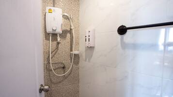 A bathroom with a shower, a hand dryer, and a towel rack.