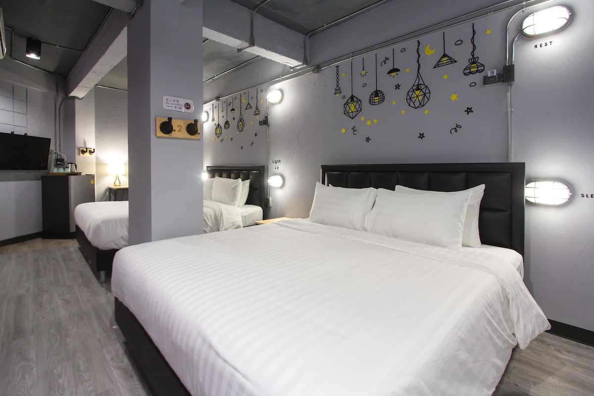 A hotel room with a large bed, two bedside tables, and a wall-mounted light fixture.