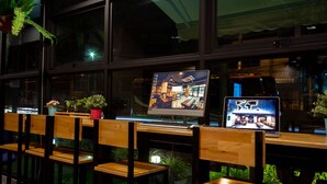 A bar area with wooden chairs and tables, two laptops on the tables, and potted plants. - Rest24 Residence (Bangkok)