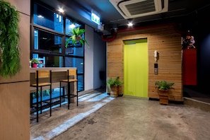 A modern interior with a bar area, wooden slatted wall, and potted plants.