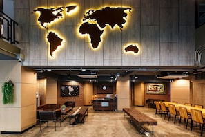 A modern restaurant with a wooden wall, a world map, and a long dining table with chairs. - Rest24 Residence (Bangkok)