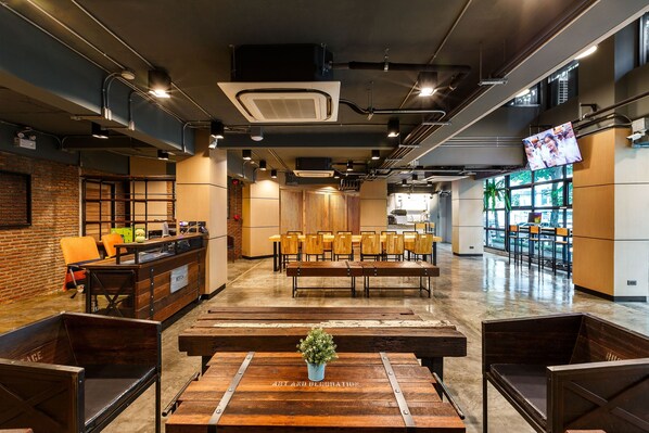 A modern interior with a reception desk, seating area, and a TV screen.