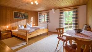 A wooden room with a bed, a table with a bowl, and a painting on the wall. - 6 people Apartment / Auerbach (Oberaudorf)