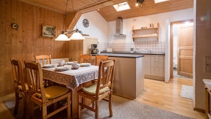 A cozy wooden interior with a dining area, kitchen, and a small island. - 6 people Apartment / Auerbach (Oberaudorf)