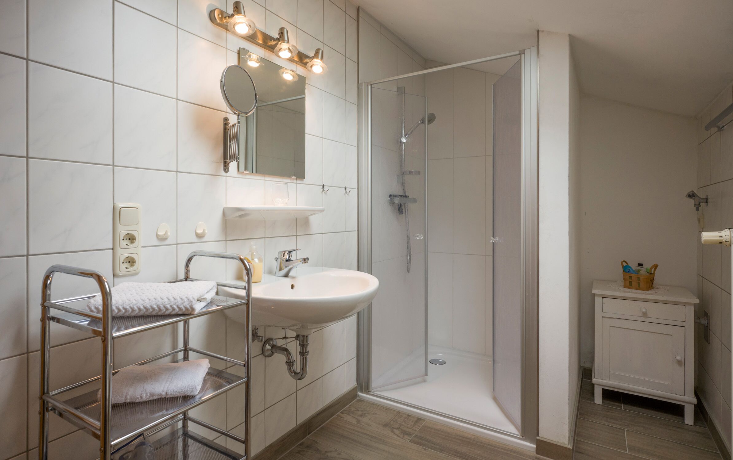 Ein modernes Badezimmer mit einer Duschkabine aus Glas, einem Waschtisch mit Spiegel und einem Handtuchhalter.