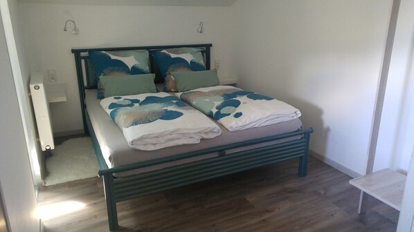 A single bed with a metal frame, a headboard with a blue abstract design, and a bedside table. - Apartment in the house Heidinger (Oberaudorf)