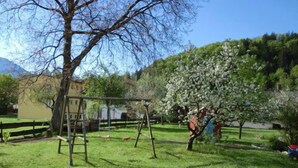 A grassy outdoor area with a swing set and a tree with white blossoms. - Apartment in the house Heidinger (Oberaudorf)