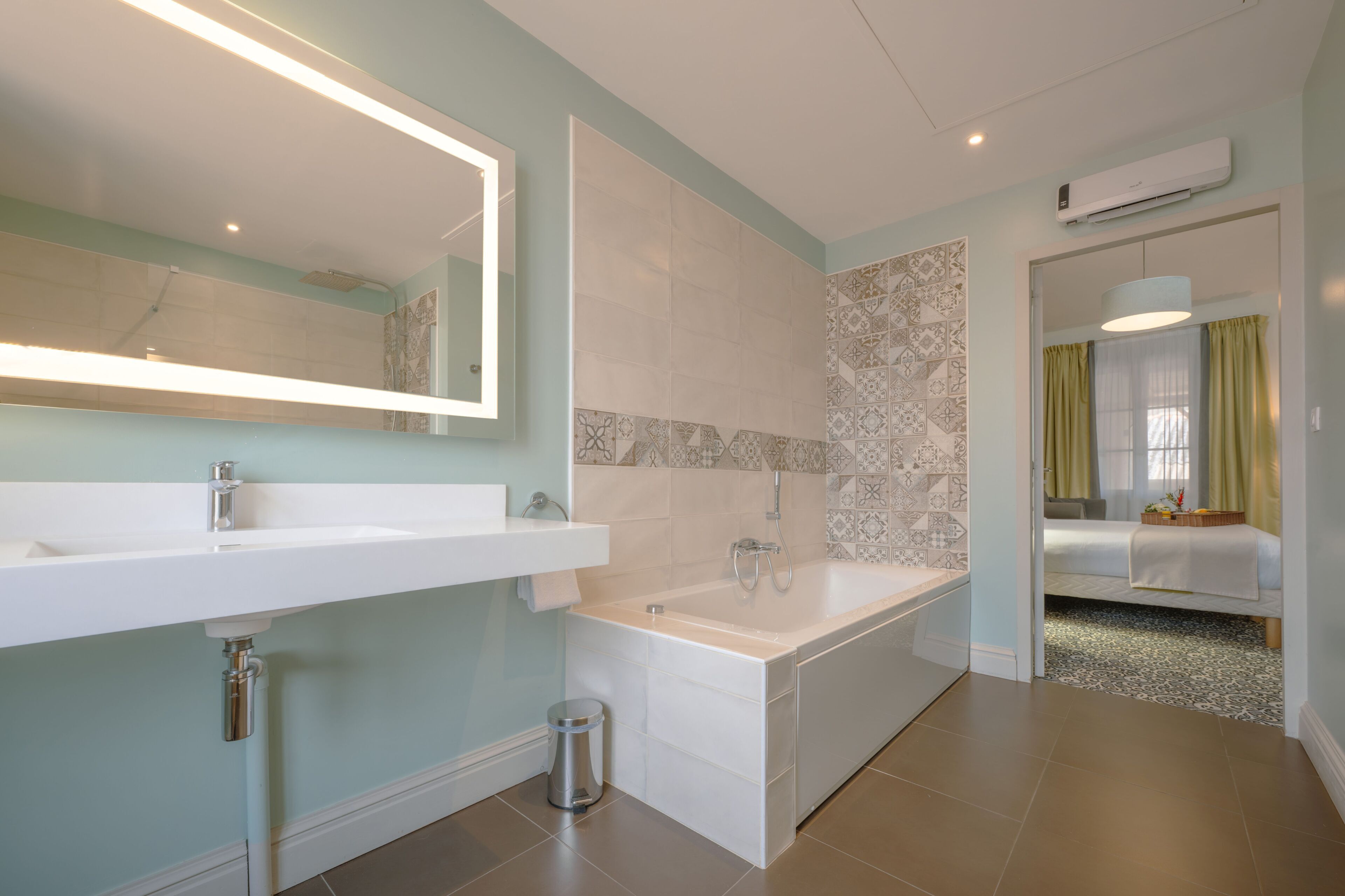 A modern bathroom with a large mirror, two sinks, a bathtub, and a shower.