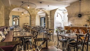 Un restaurante con varias mesas y sillas, una zona de bar y paredes de piedra en arco.