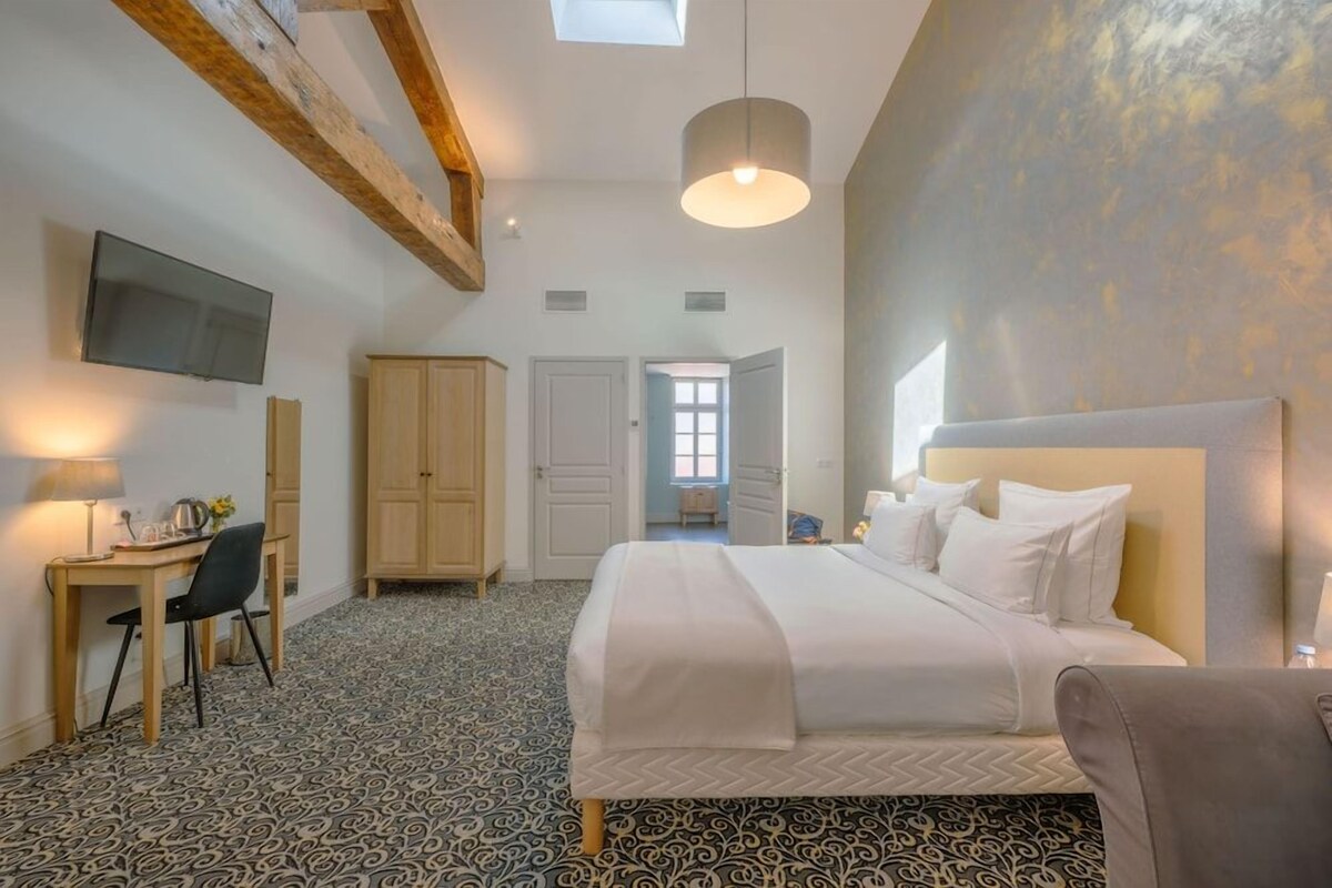 A bedroom with a bed, a desk, a chair, a television, and a wardrobe.
