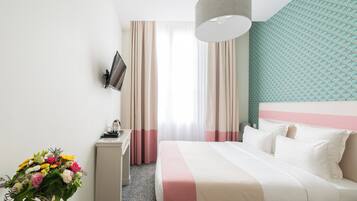 Une chambre d’hôtel avec un lit, un bureau, une télévision et une fenêtre avec des rideaux.