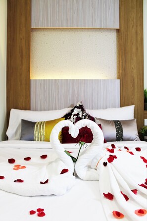 Una cama impecable con pétalos de rosa y una disposición de toallas en forma de corazón.