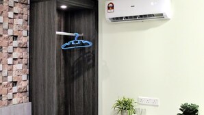 Casa de banho compacta com chuveiro, porta-toalhas, uma pequena mesa com uma planta e um secador de cabelo.